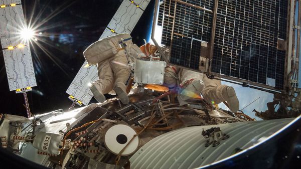 TWO COSMONAUTS EXIT STATION AND BEGIN SPACEWALK